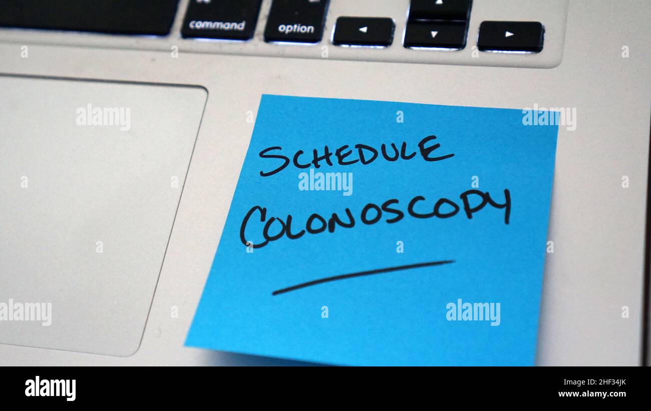 Nota adhesiva recordatorio para programar la colonoscopia, una prueba para el cáncer colorrectal. Foto de stock