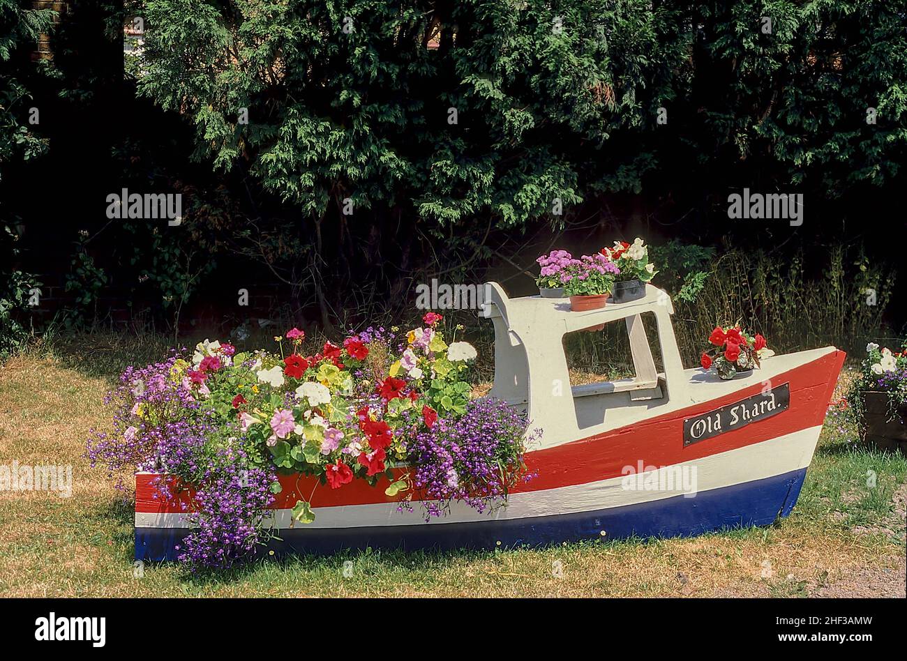 Pequeño barco utilizado para una exhibición de flores al borde de la carretera. Llamado Old Shard después de que el viejo puente de peaje fue demolido y reemplazado por un nuevo puente moderno de peaje gratuito. Foto de stock