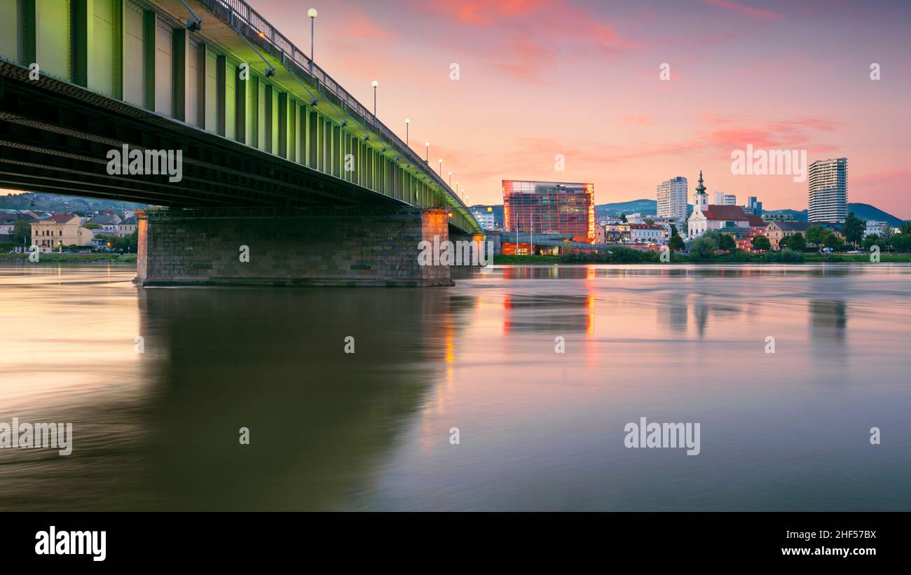 Linz, Austria. Paisaje urbano Imagen de la ribera de Linz, Austria al atardecer de verano con reflejo de las luces de la ciudad en el río Danubio. Foto de stock