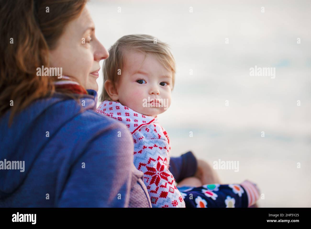 Mamá e hija en los suéteres calientes están en la orilla del mar de invierno. Relajación. La familia pasa tiempo en la naturaleza. Vacaciones. Foto de stock