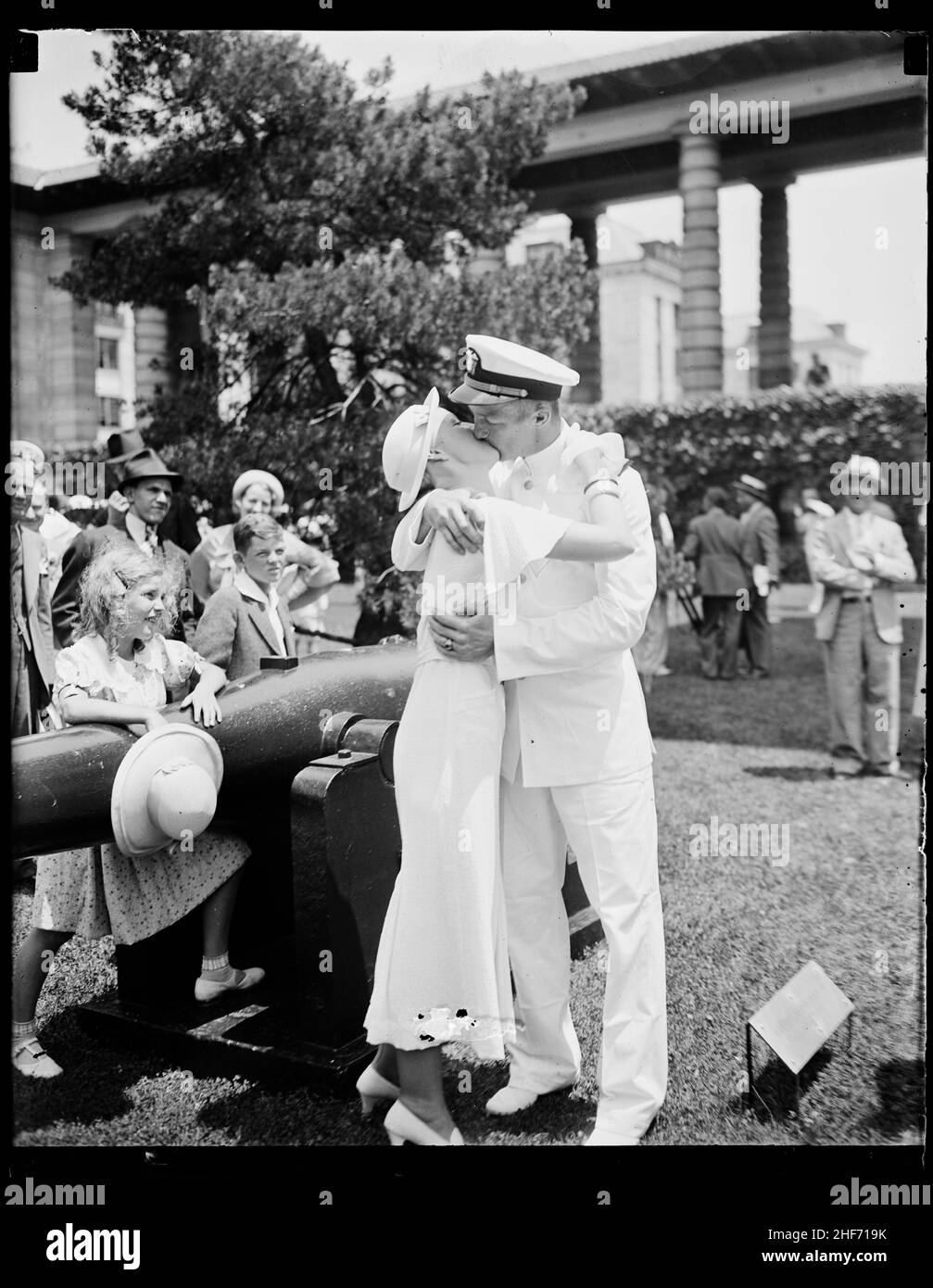 Después de ceremonias de graduación en la Academia Naval de los Estados Unidos, un nuevo oficial besa a su niña. En el fondo, una niña y un niño tienen diferentes reacciones al beso, Annapolis, MD, 1935. Foto de stock