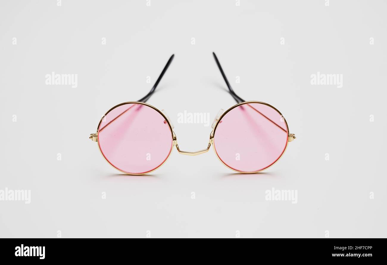 Gafas de sol con lentes de color rosa y marco metálico redondo dorado aislado sobre fondo blanco, recortado, elemento de diseño Foto de stock