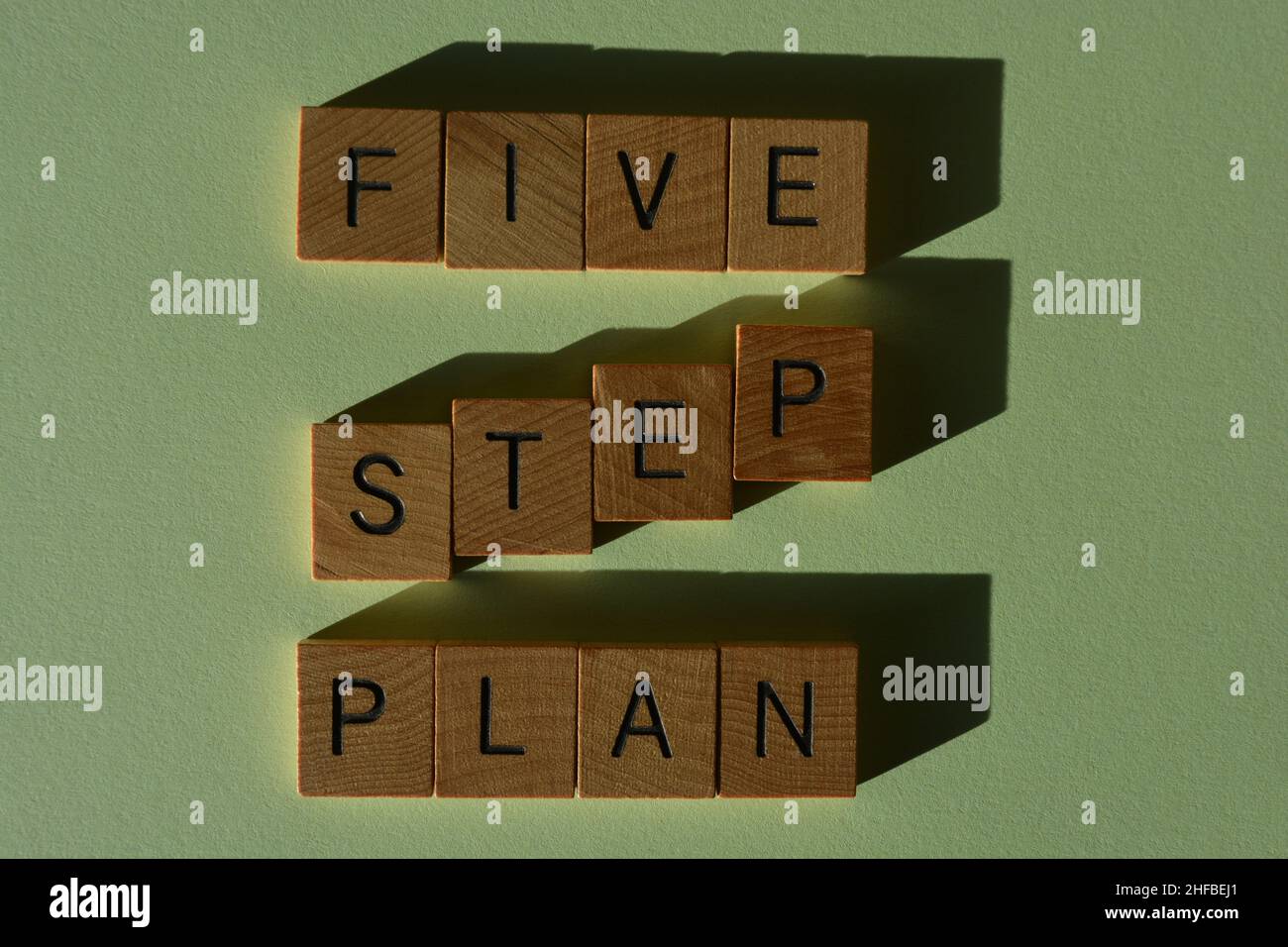 Plan de cinco pasos, palabras en letras del alfabeto de madera aisladas sobre fondo verde Foto de stock
