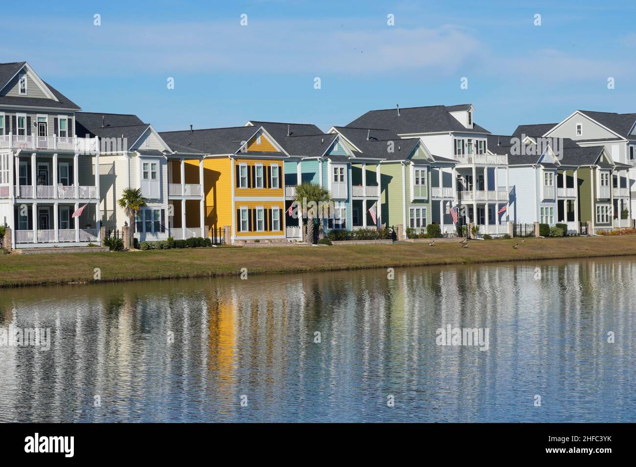 Casas de colores brillantes reflejadas en un estanque en un barrio suburbano en Carolina del Sur Foto de stock