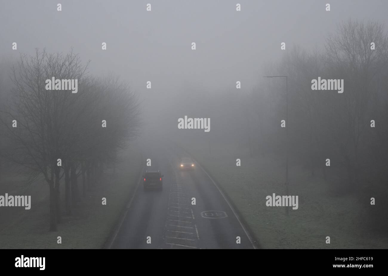 Una carretera foggy que muestra los vehículos con sus faros encendidos. Foto de stock