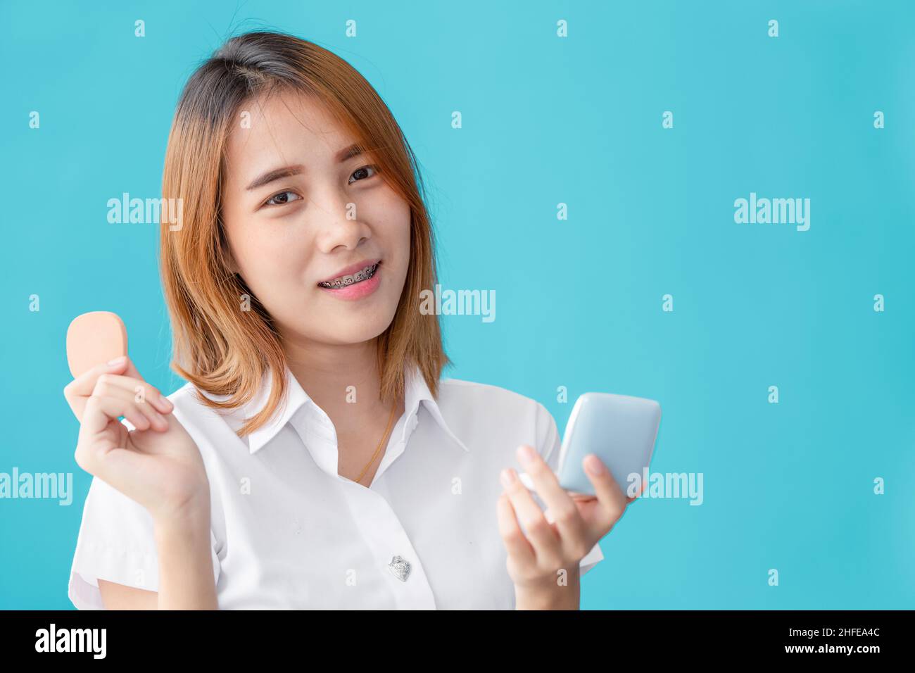 Universidad asiática adolescente mano sosteniendo maquillaje cara polvo belleza feliz sonrisa Foto de stock