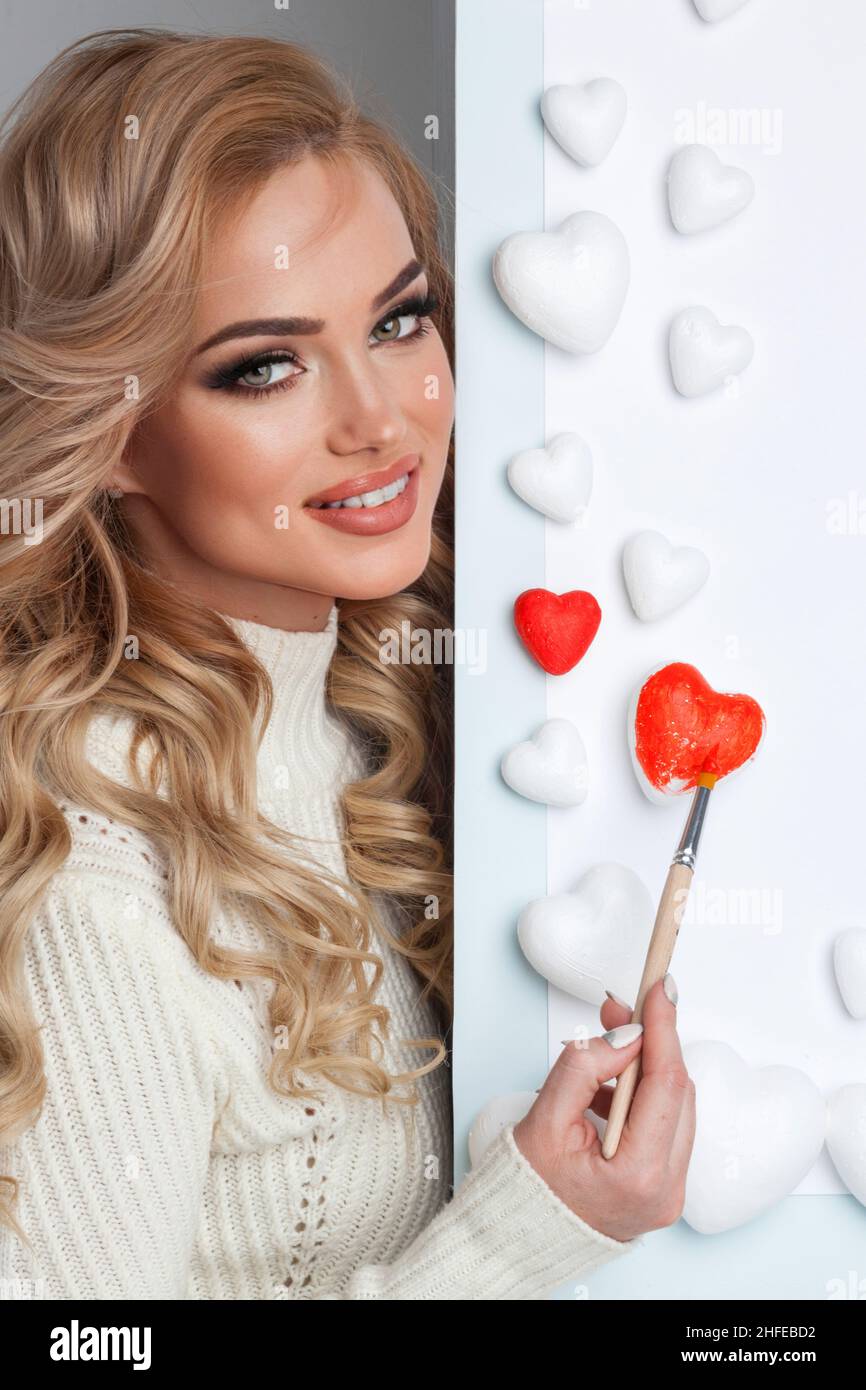 Hermosa mujer joven pintando corazones con pintura roja Valentine día amor concepto Foto de stock