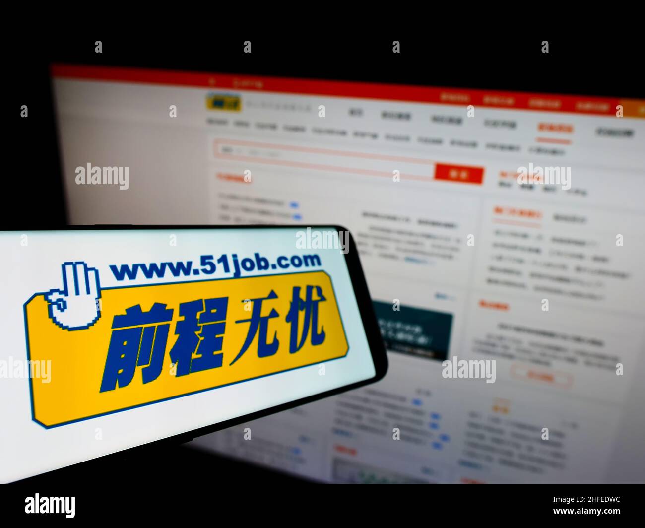 Teléfono móvil con el logotipo de la empresa china de recursos humanos 51job Inc. En la pantalla frente al sitio web empresarial. Enfoque a la izquierda de la pantalla del teléfono. Foto de stock