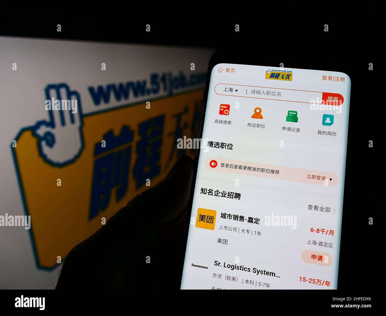 Persona que sostiene el teléfono móvil con el Web site de la compañía china de los recursos humanos 51job inc. En la pantalla delante del logotipo. Enfoque en el centro de la pantalla del teléfono. Foto de stock