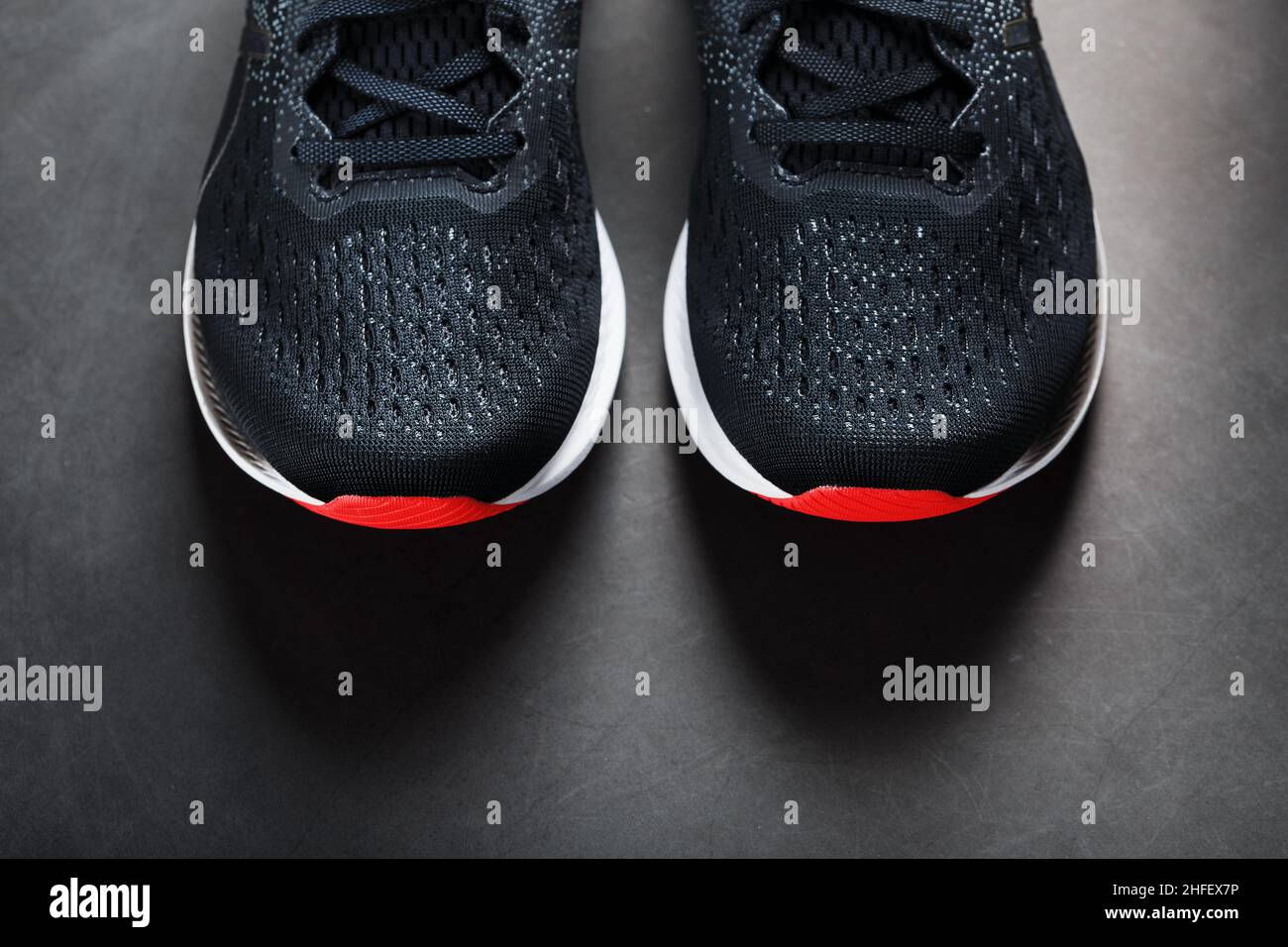 Zapatillas deportivas negras suela roja sobre fondo negro. Espacio libre Fotografía de stock -