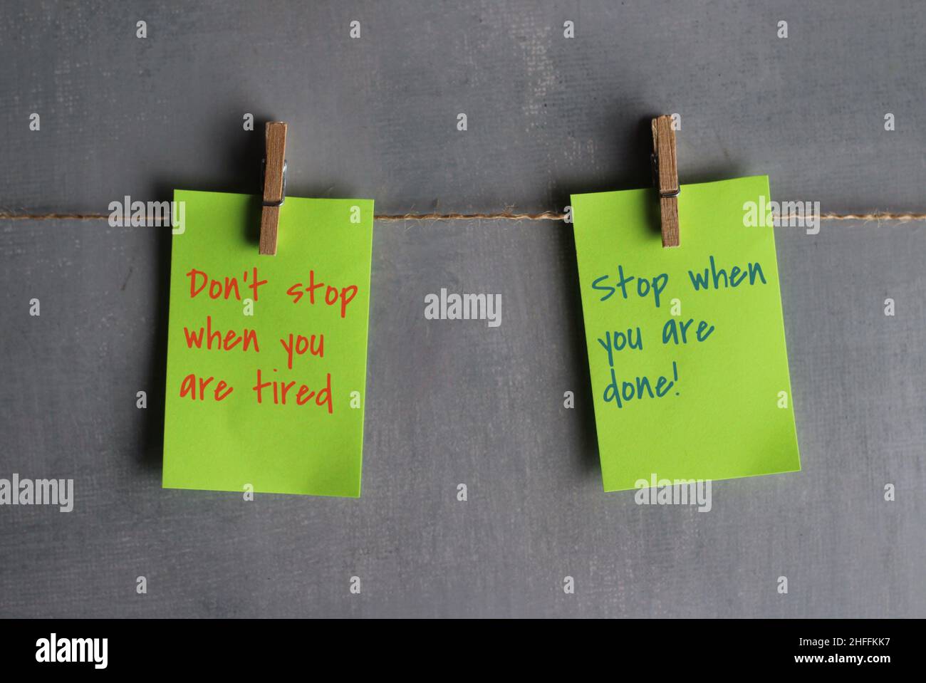 Las citas motivacionales ' no se detienen cuando usted está cansado, se detienen cuando usted está hecho!' sobre papeles colgados de la cuerda contra la pared de hormigón. Foto de stock