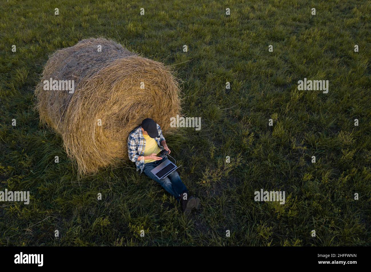 Granjero con computadora portátil en el campo. Punto de vista drone. Digitalización de agricultura y agricultura inteligentes Foto de stock