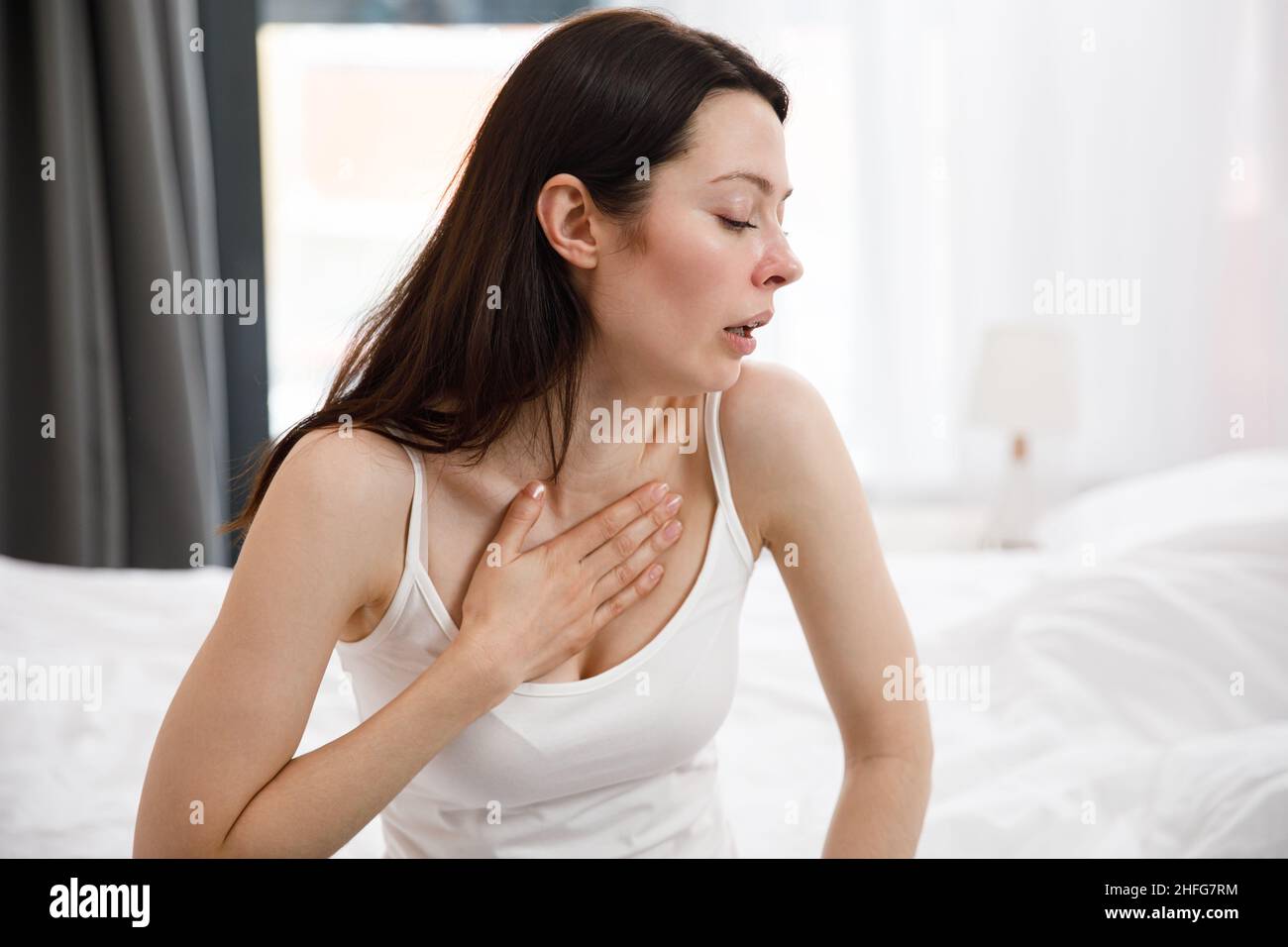 Retrato de una joven malsana que tose mucho, que sufre de tos, tiene dolor en el pecho. La mujer enferma y desesperada tiene gripe. Frío, enfermedad Foto de stock