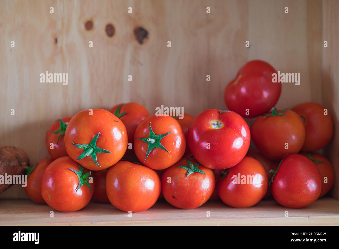 Grupo de tomates apilados en caja de madera Foto de stock