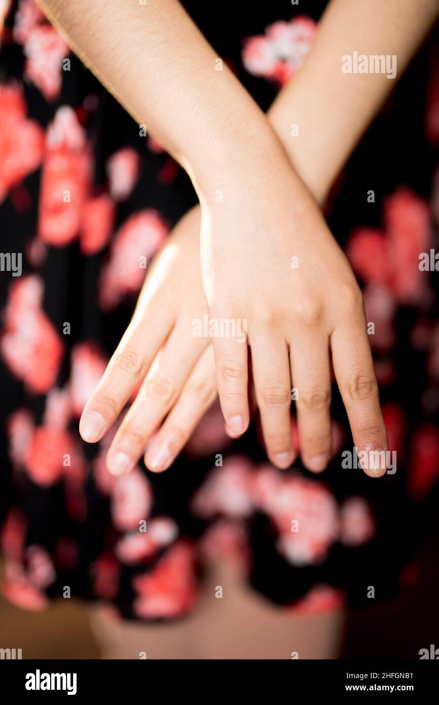 Mujer con las manos cruzadas delante de su vestido con estampado floral Foto de stock