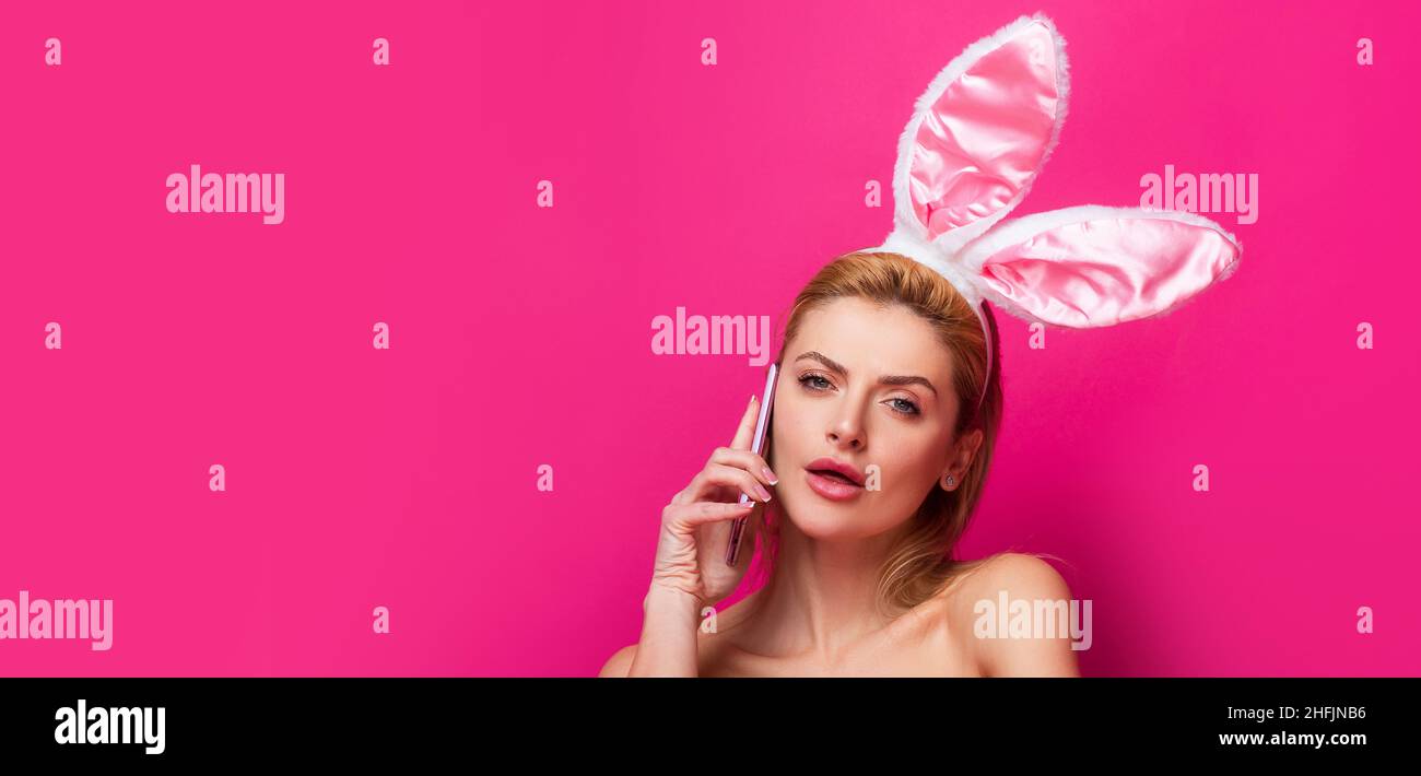 Bandera de Pascua con mujer conejita. Mujer de Pascua con orejas de conejo hablando por teléfono, aislado en rosa. Foto de stock