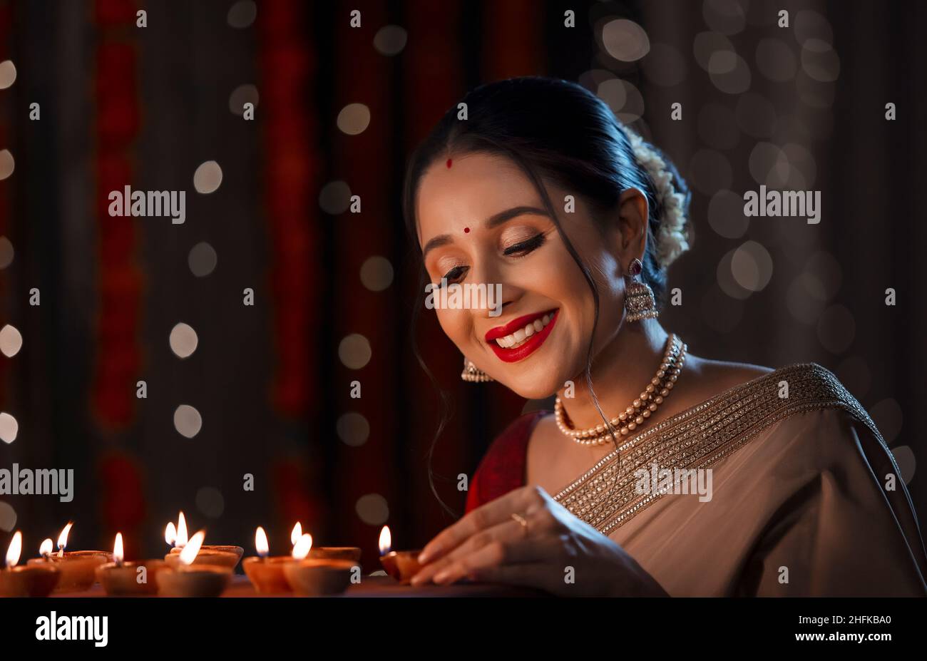 Hermosa mujer india poniendo diya con una sonrisa en casa en Diwali Foto de stock