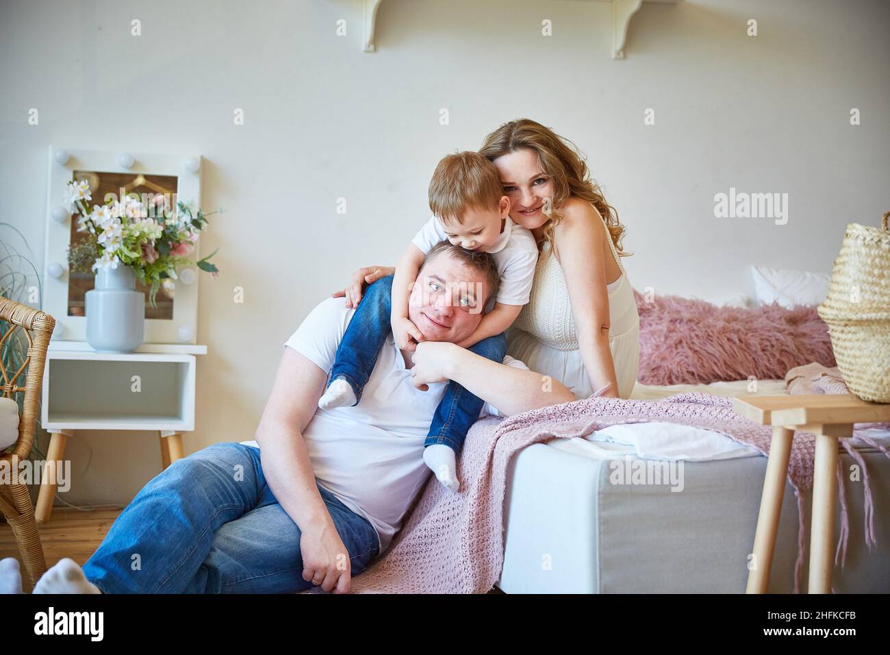 familia joven con un hijo en el dormitorio sentado en la cama Foto de stock
