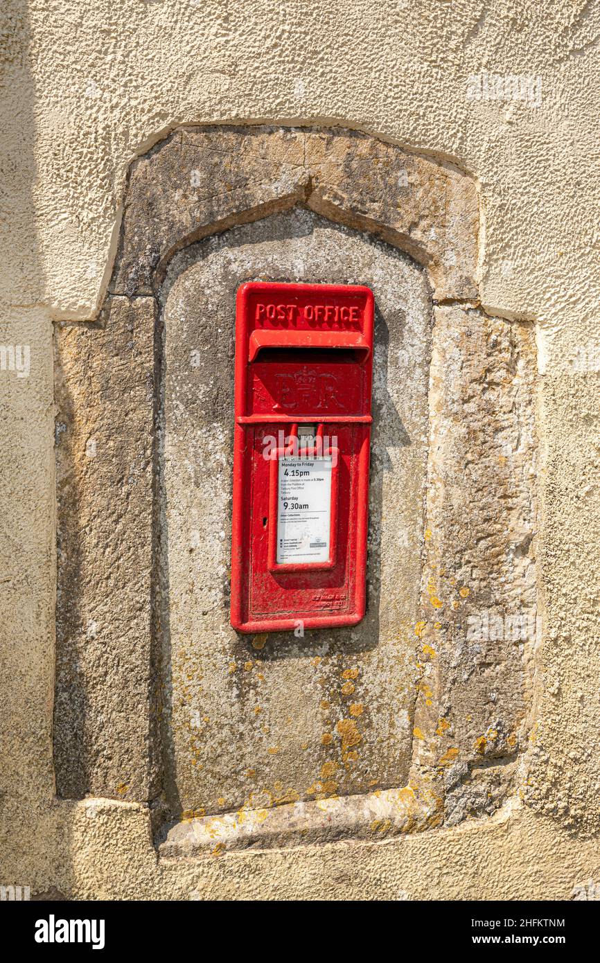 ER Elizabeth II caja de correos roja insertada en una antigua ventana de piedra moldura en la pared de una antigua granja en la aldea Cotswold de Hawkesbury, Gloucester Foto de stock