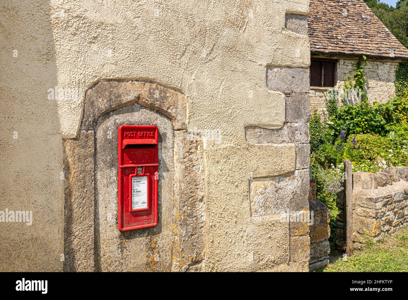 ER Elizabeth II caja de correos roja insertada en una antigua ventana de piedra moldura en la pared de una antigua granja en la aldea Cotswold de Hawkesbury, Gloucester Foto de stock