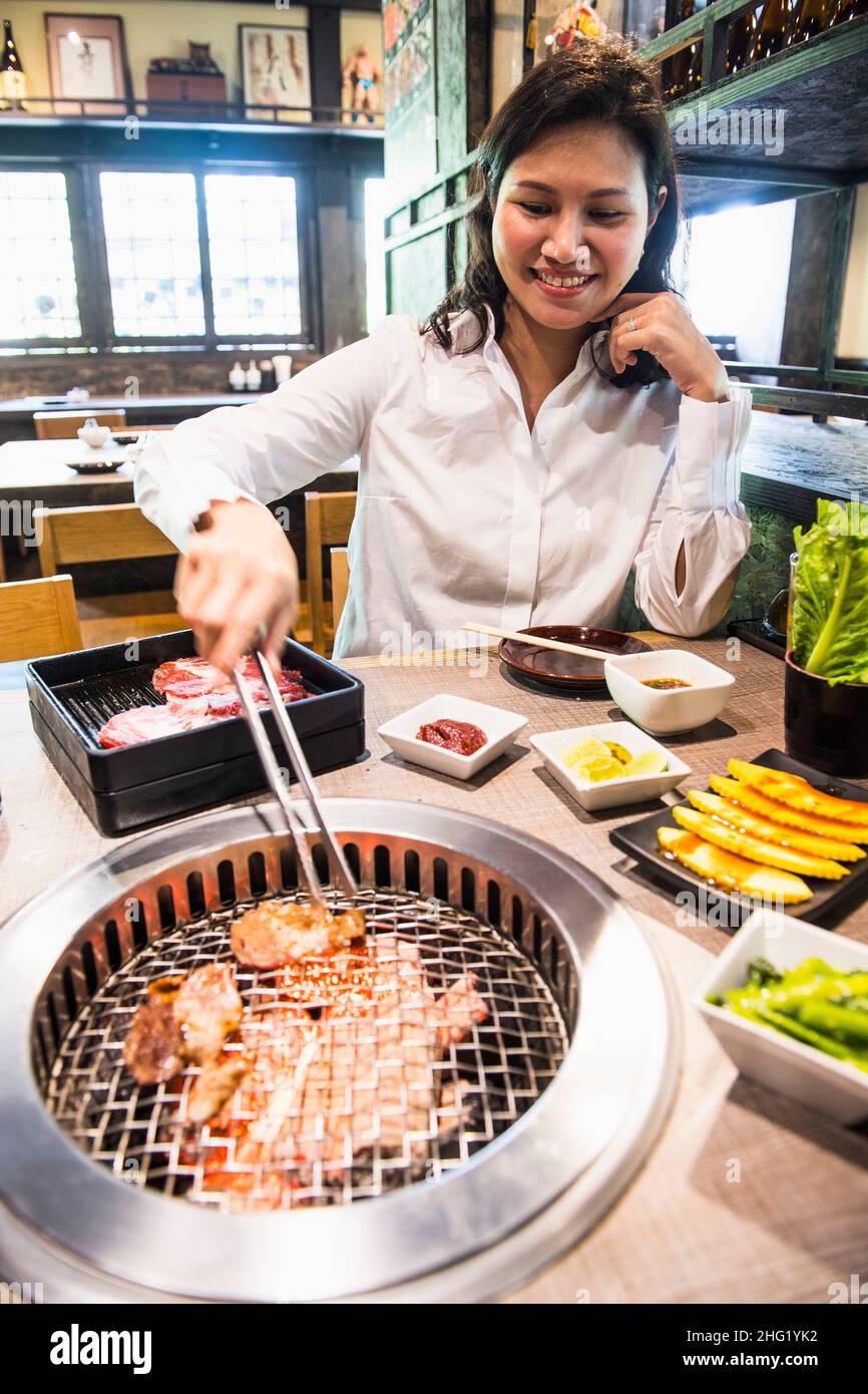 Mujer parrillando carne en el restaurante tailandés Foto de stock