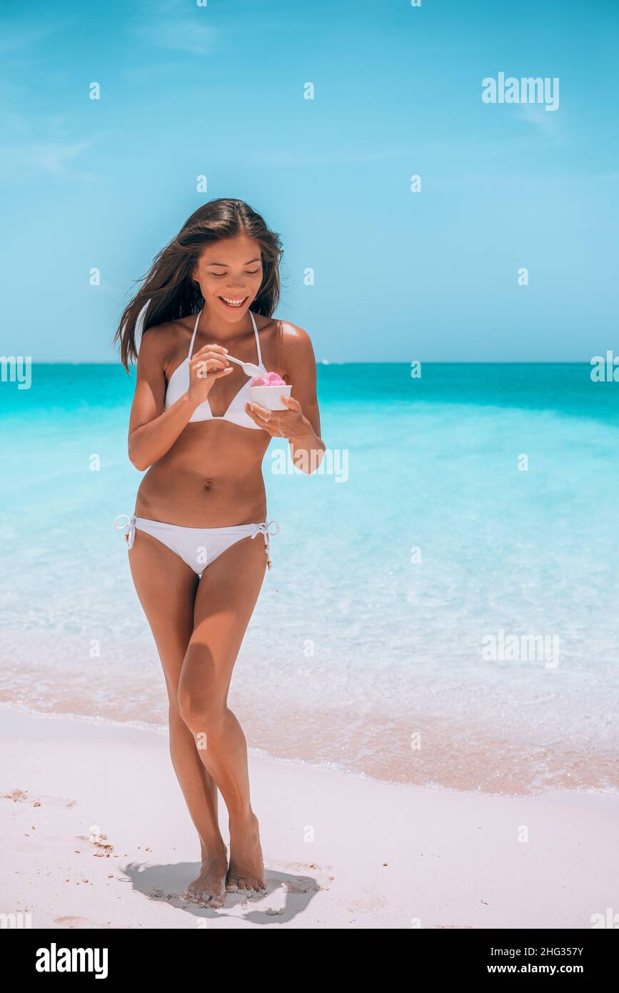 Helado mujer bikini comer postre congelado en la playa. Cultivo vertical de  traje de baño asiático modelo en cuerpo sano en el Caribe isla destino  Fotografía de stock - Alamy