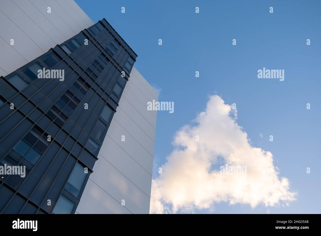 Mirando hacia arriba al edificio residencial y a la rara cloiud en una forma de triángulo con cielo azul y espacio de copia Foto de stock