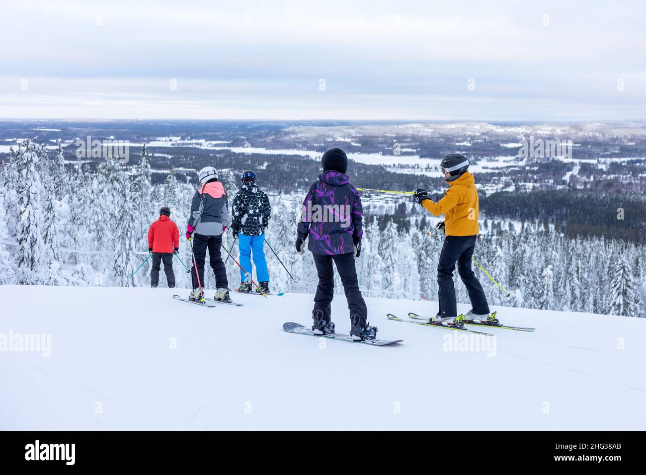 Vuokatti, Finlandia - January2022: Esquiadores y snowboarders en la cima de la colina preparándose para esquiar por la pista en la estación de esquí de Vuokatti. Foto de stock