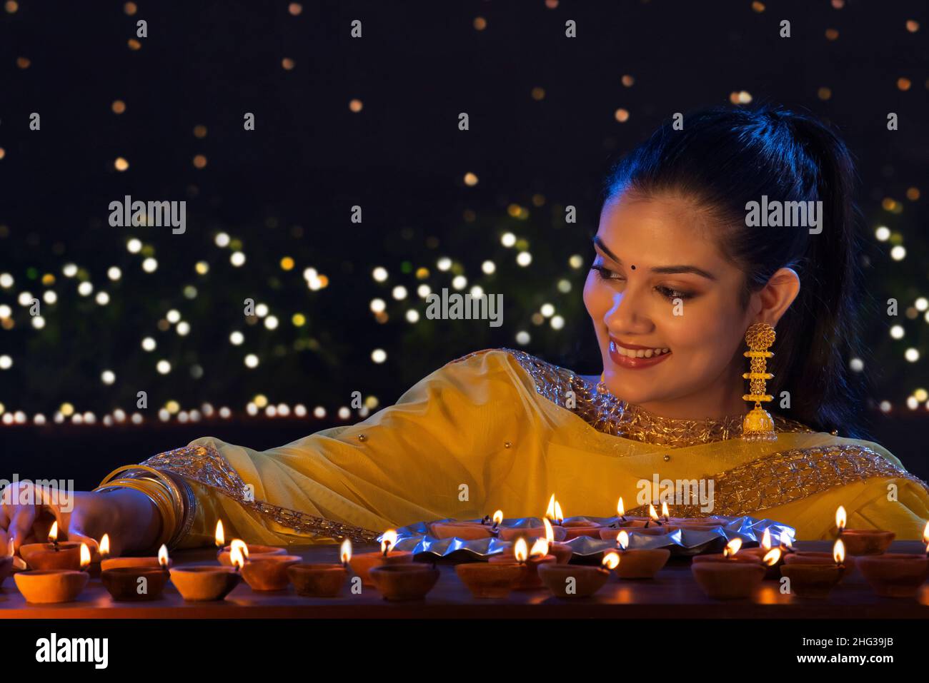 Hermosa chica india poniendo diyas con sonrisa en la ocasión de Diwali Foto de stock
