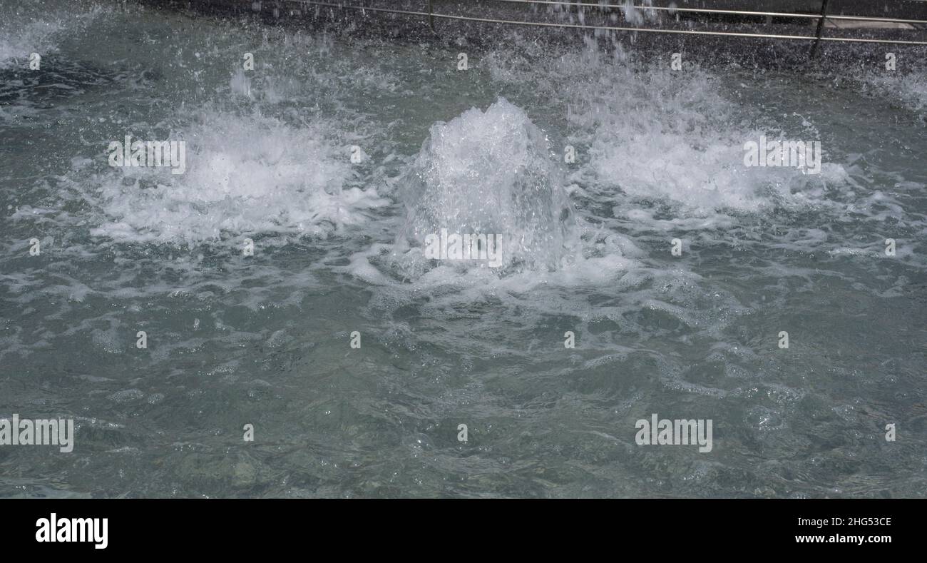 fuentes de agua burbujeantes en una cuenca con superficie ondulada en una ciudad Foto de stock