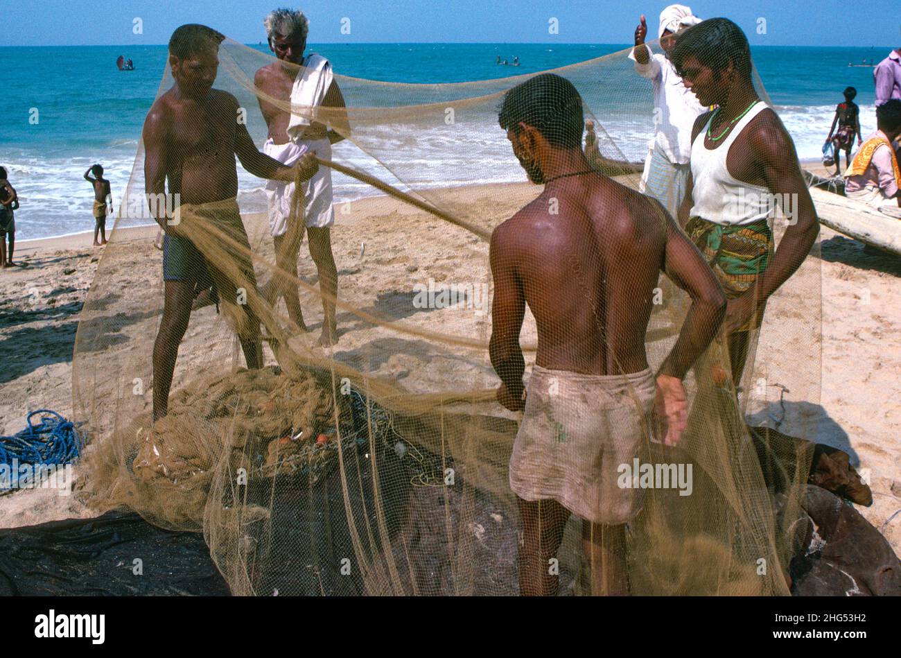 Pescadores clasificando sus redes en la playa. Kerala, sur de la India Foto de stock