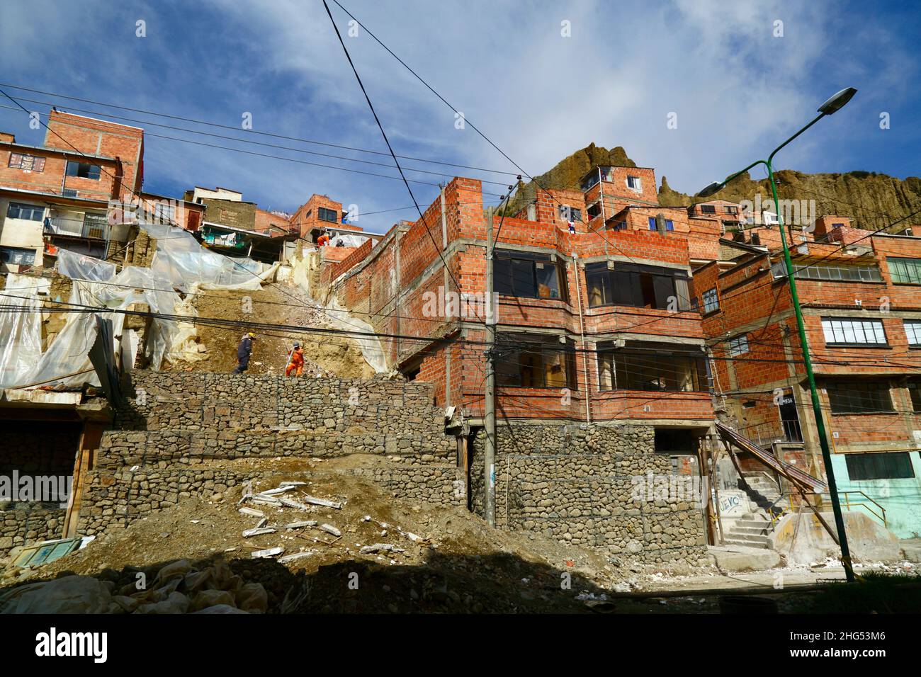 La Paz, Bolivia: Trabajadores municipales que se encuentran en una ladera y han dañado casas con jaulas llenas de rocas / gaviones en un sitio en Tembladerani / distrito de Cotahuma, donde la excavación no autorizada y el movimiento de la tierra causaron el colapso de parte de la ladera. Muchos de los barrios de la ladera de La Paz han sido construidos en áreas inestables sin permisos adecuados o controles de construcción. El hundimiento y la erosión que provocan el derrumbe de los deslizamientos de tierra y las casas son comunes, especialmente en la estación lluviosa. En este incidente, hubo que demoler 2 casas y otras 6 resultaron gravemente afectadas. Foto de stock