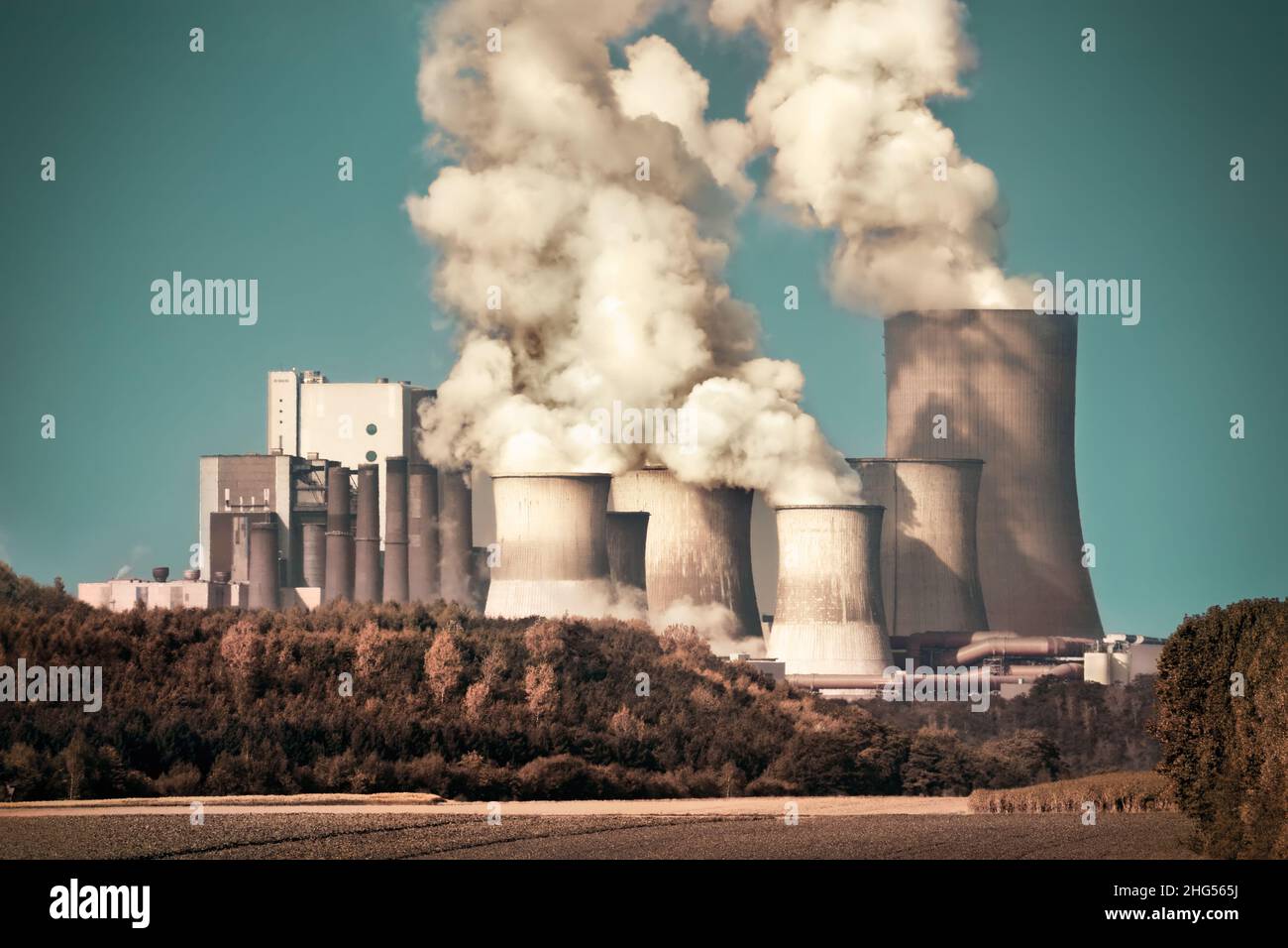 Gran central de carbón con vapor y humo en el cielo azulado, aspecto dramático Foto de stock