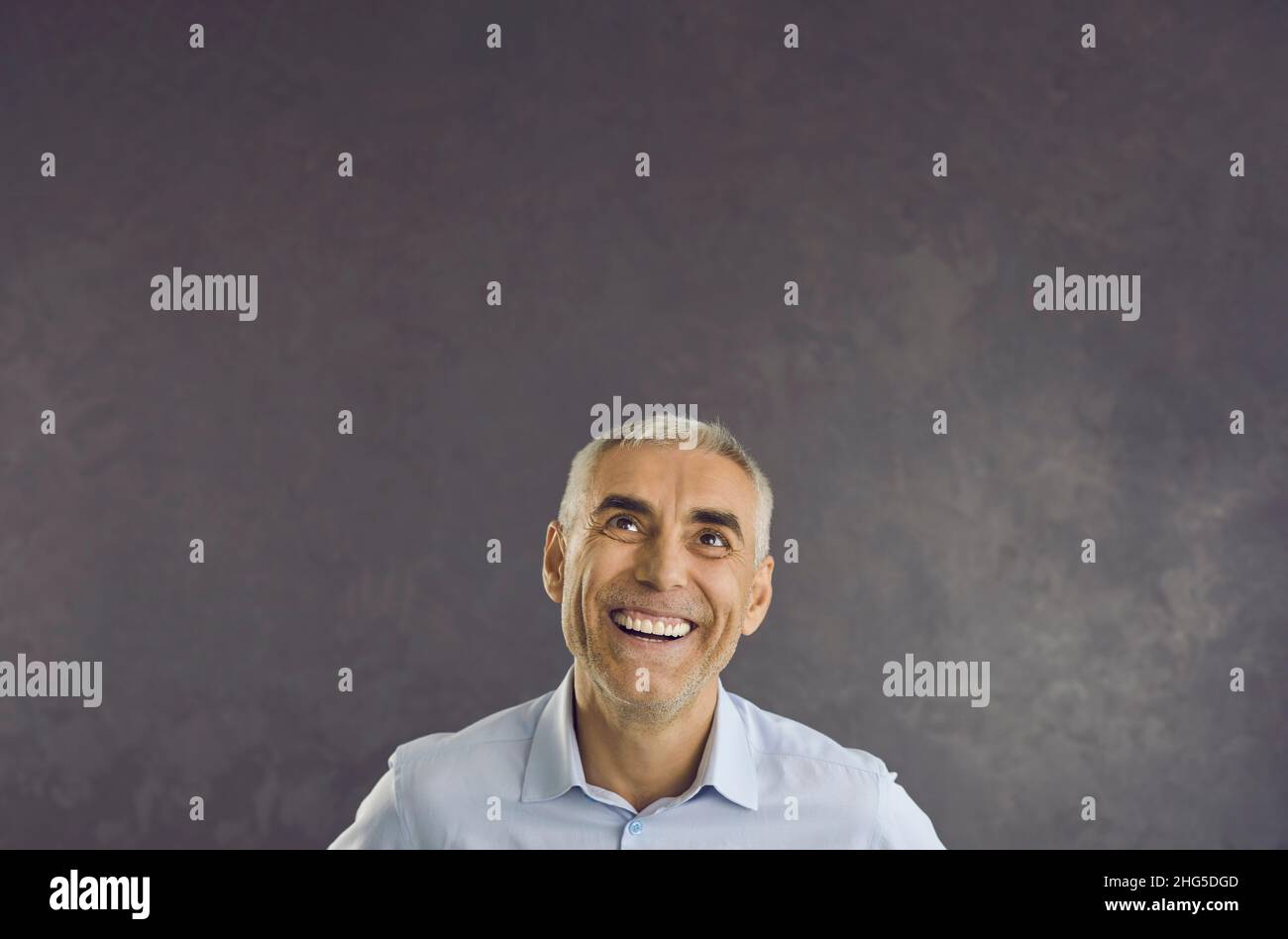Sonriente hombre de mediana edad mira hacia arriba en el espacio de copia en blanco Foto de stock