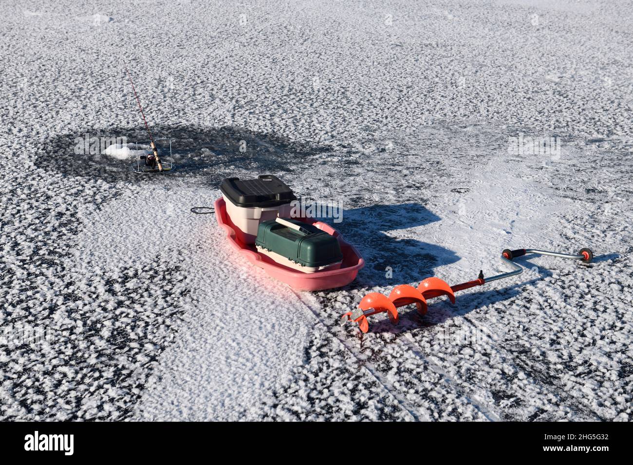 Caña de pesca en el agujero con trineo y barrena para la pesca en el hielo en el primer hielo del invierno en la bahía Kempenfelt congelada en el lago Simcoe Barrie Ontario Foto de stock