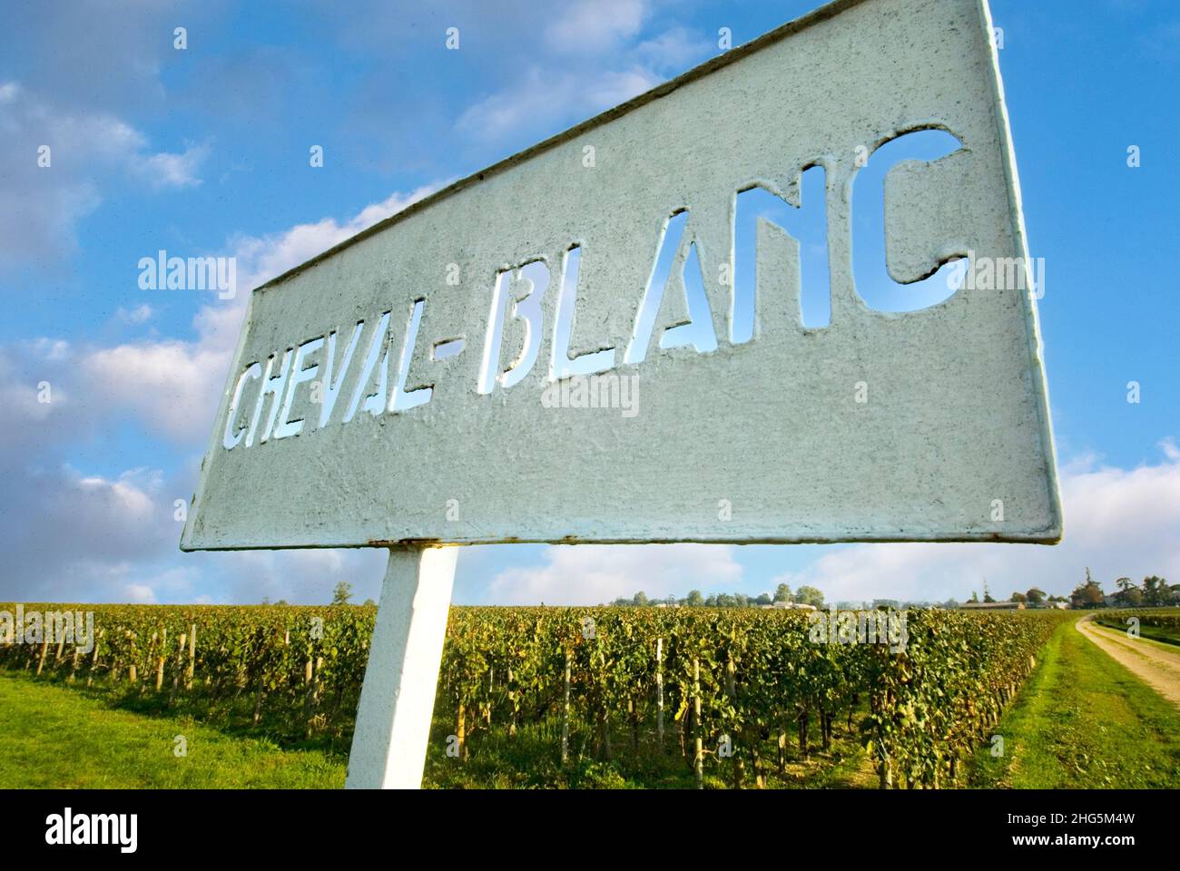 Château Cheval Blanc señal de entrada y viñedos con cielo azul, en la entrada a la famosa y fina producción de vinos rojos Grand Cru classé en Saint-Émilion, región vinícola de Burdeos de Francia señal Cheval Blanc con viñedo otoñal detrás de Saint Emilion Gironde Francia Foto de stock