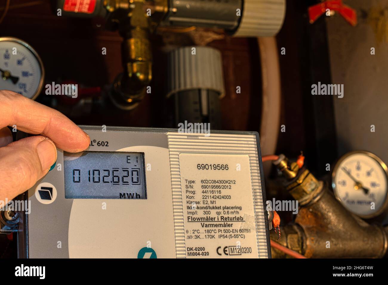 Dos dedos controlan kilovatios hora del medidor digital del sistema de calefacción de distrito, Dinamarca, 18 de enero de 2022 Foto de stock