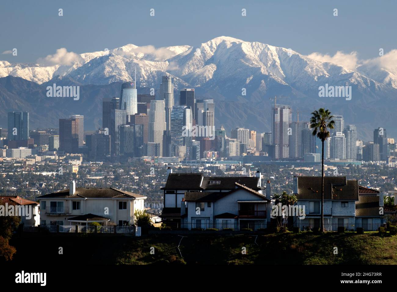 Picos nevados de las montañas San Gabriel detrás del horizonte de la ciudad de Los Ángeles en un día despejado Foto de stock