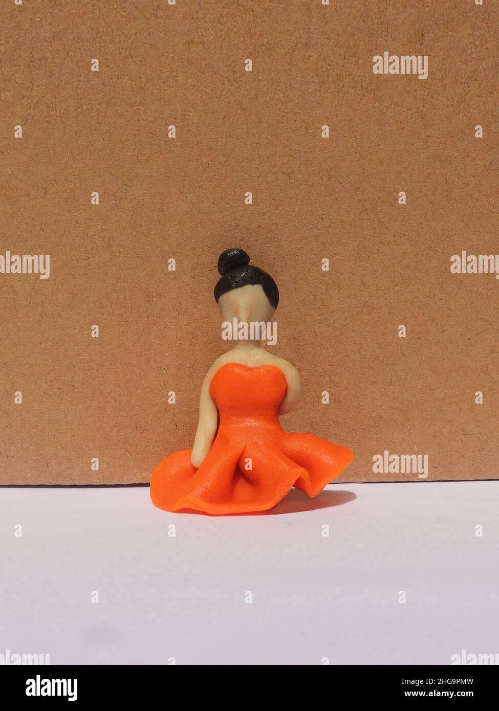 Niña de color naranja vestido figurita hecha de arcilla plastificina Foto de stock