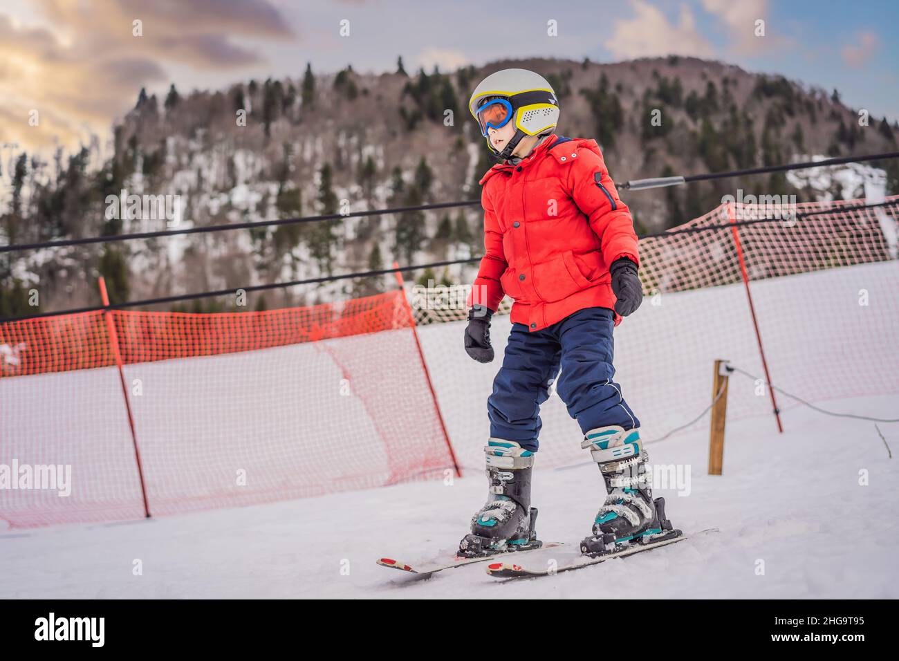 Esquí infantil en las montañas. Niño activo con casco de seguridad, gafas y  bastones. Carrera de esquí para niños pequeños. Deporte de invierno para la  familia. Esquí para niños Fotografía de stock -
