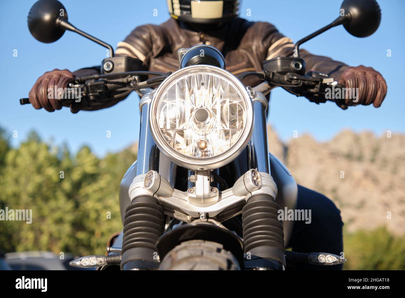 Motocicleta con faro encendido y persona irreconocible Foto de stock