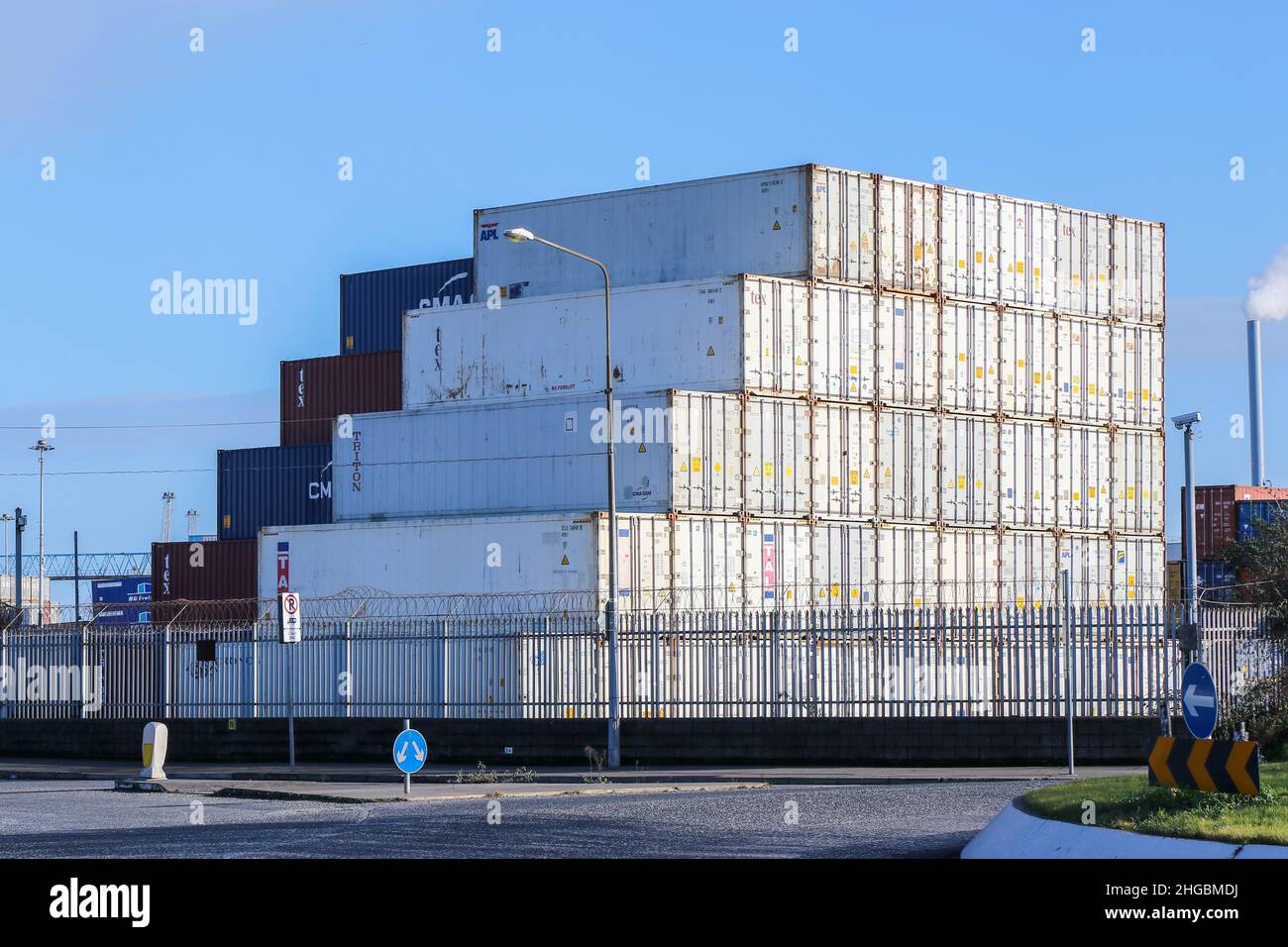 Pila de cajas de envío blancas en diseño escalonado con patrón lineal. Contenedores azules y marrones más allá. Industria del transporte marítimo en el puerto. Dublín, Irlanda Foto de stock