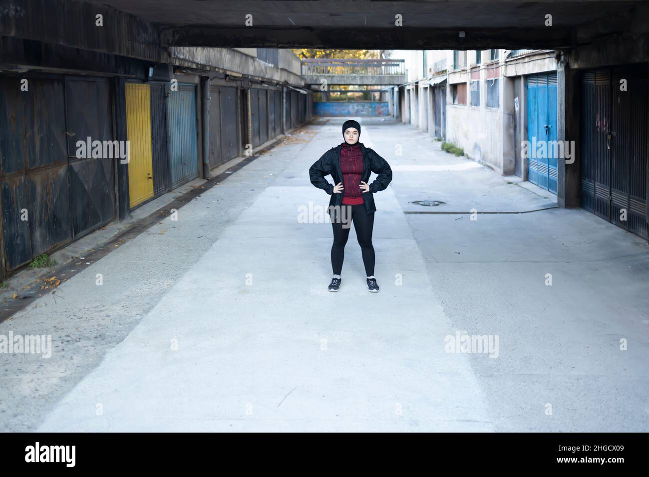 Mujer musulmana deportiva de pie determinada en un callejón Foto de stock