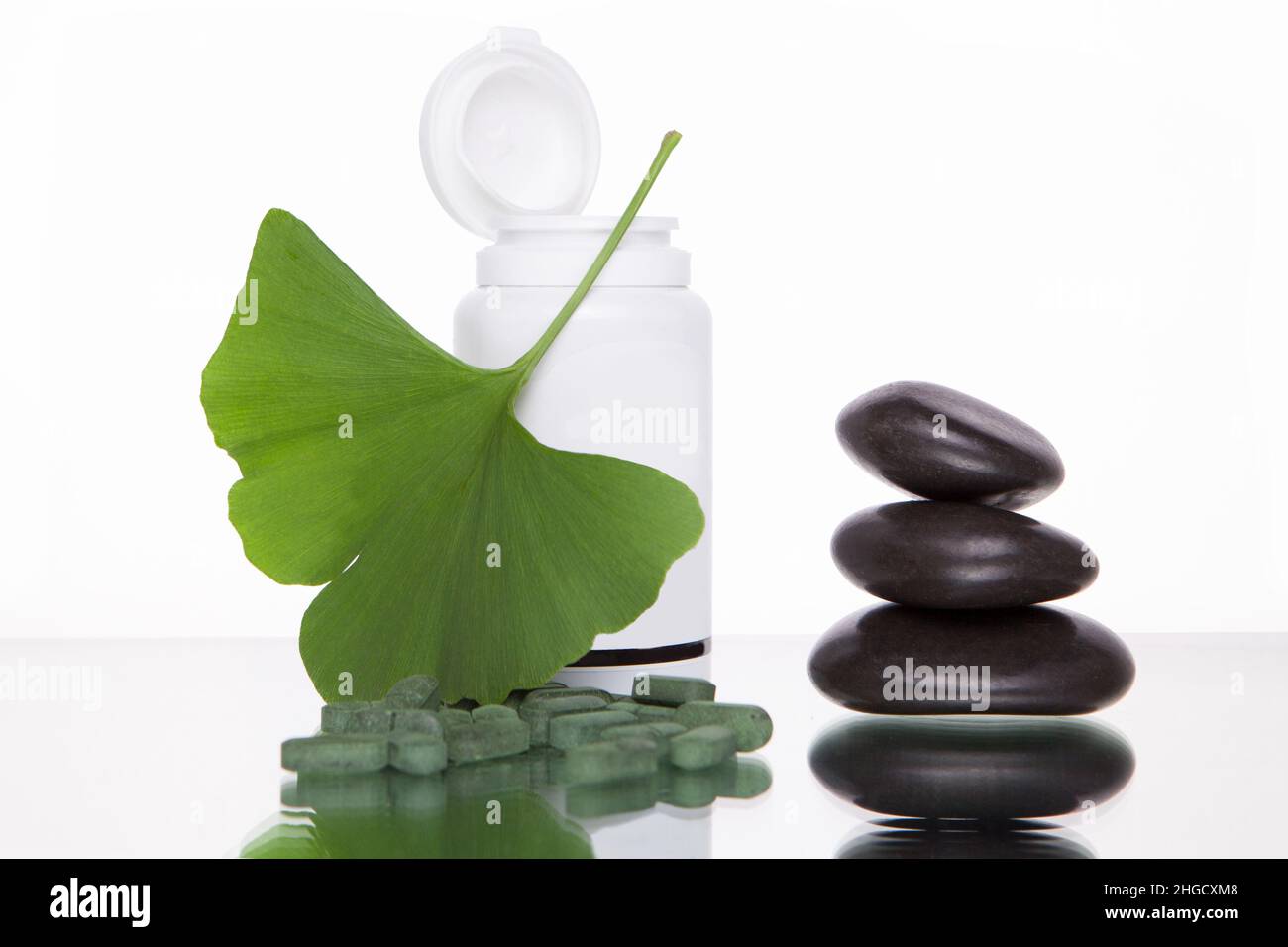 El extracto de la píldora de Ginkgo Biloba y las hojas verdes frescas de Ginkgo Biloba con el envase abierto son más adecuados para los anuncios de medicina alternativa de adultos mayores. MOCKU Foto de stock
