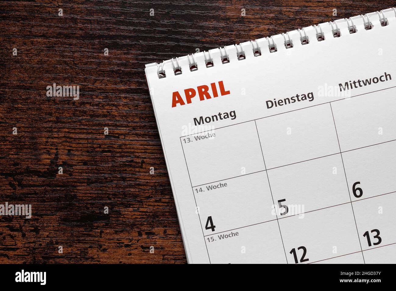 mes de abril en calendario alemán o planificador sobre escritorio de madera Foto de stock