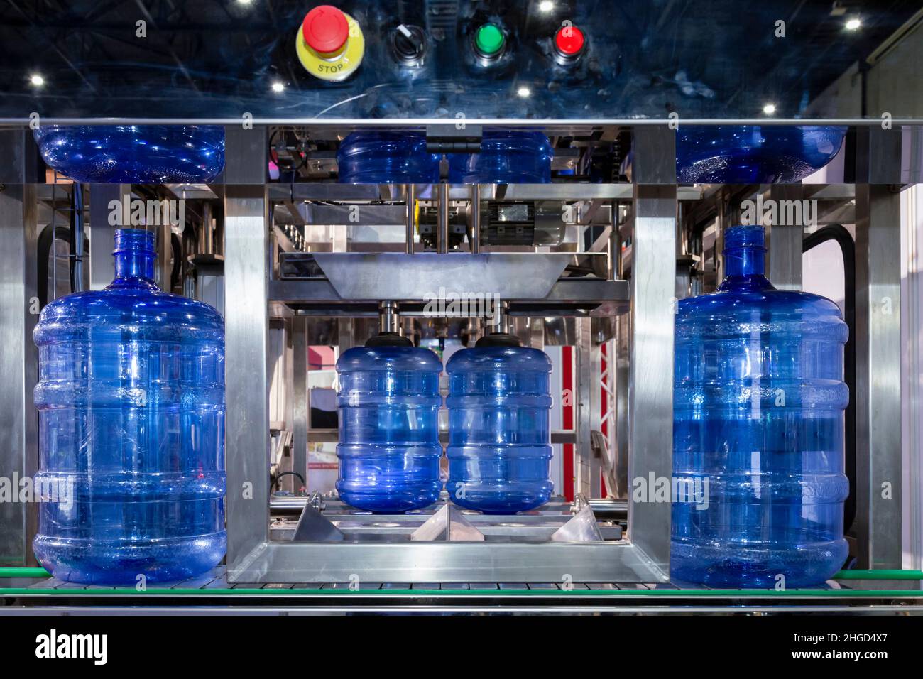 Depósito de almacenamiento de agua de PE azul o botella de PEA en la línea de producción de la cinta transportadora en la máquina de llenado de bebidas en la fabricación de agua potable. Foto de stock