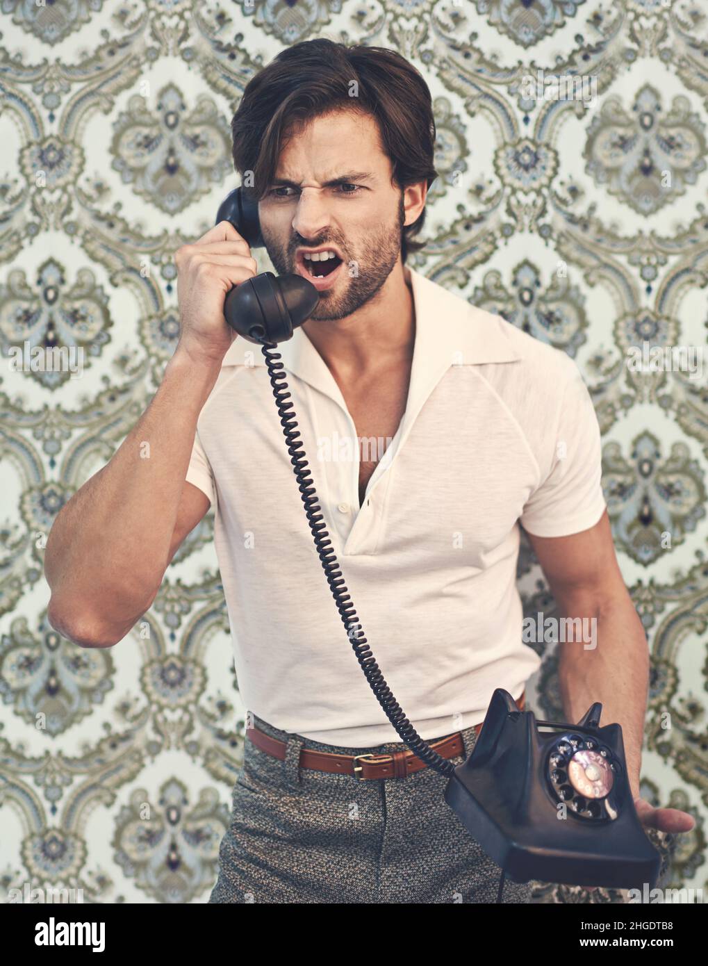 HECHO Un hombre guapo con ropa retro 70s gritando a alguien en teléfono Fotografía de stock - Alamy