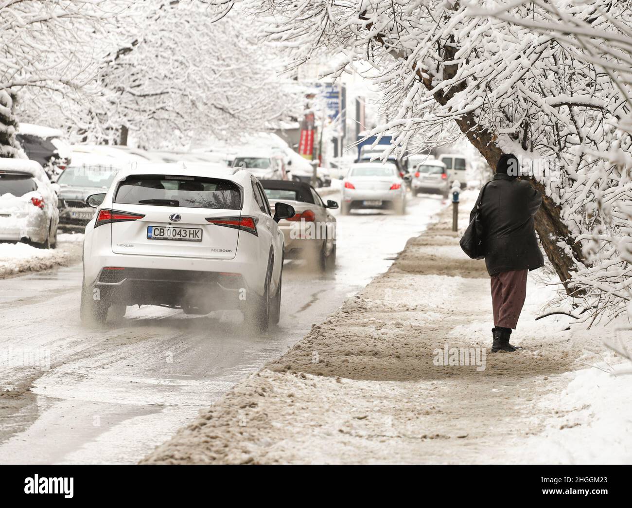 La gente camina sobre una acera sucia cubierta de hielo peligroso después de nevar en Sofía, Bulgaria el 21 de enero de 2022 Foto de stock