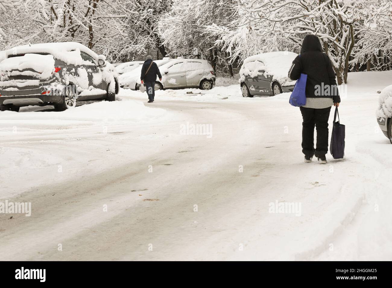 La gente camina por una calle sucia cubierta de hielo peligroso después de nevar Foto de stock