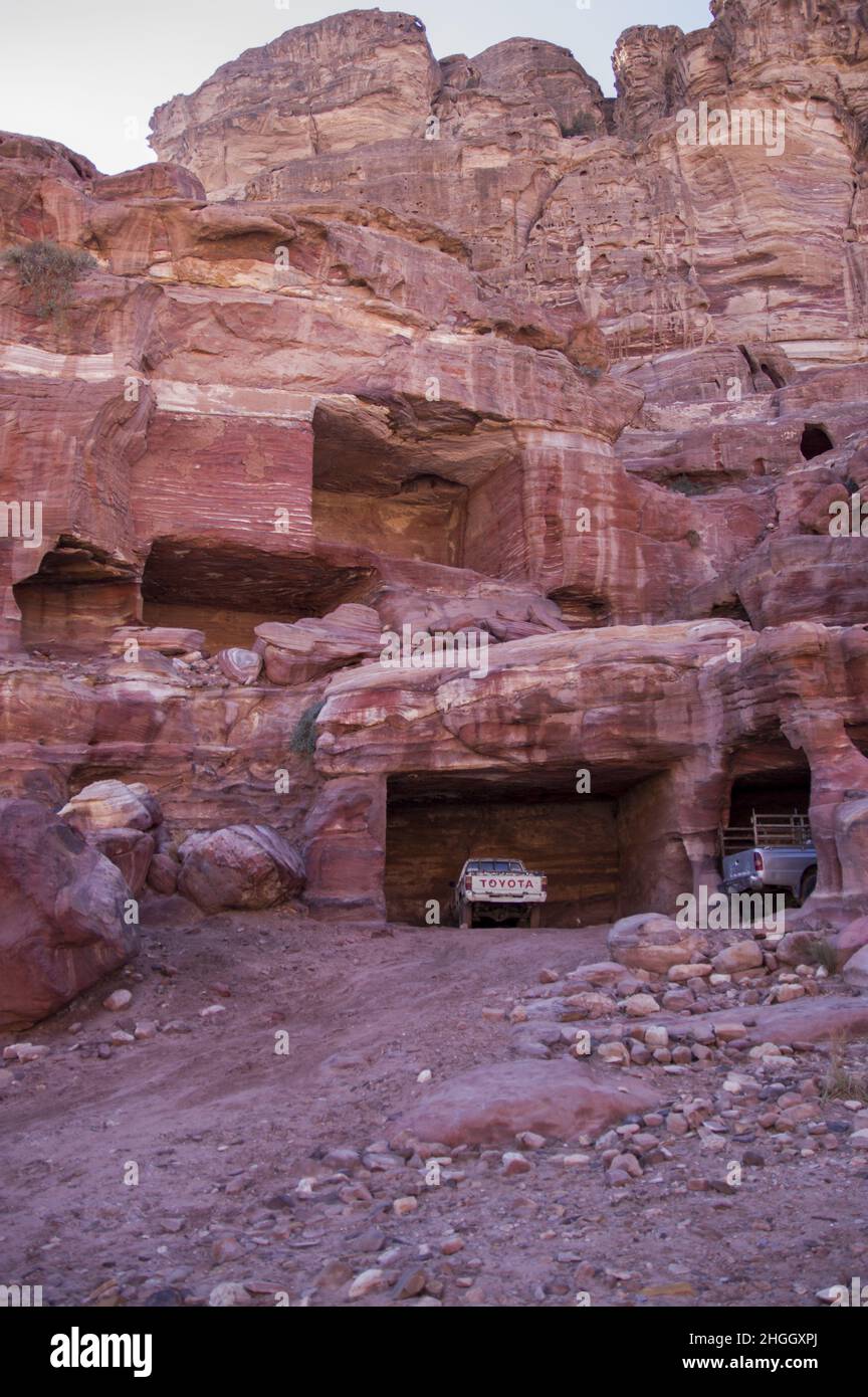Toyota camionetas estacionadas en antiguas estructuras nabateas en Petra, Jordania en medio de cañones, cuevas, paisaje desértico y edificios. Foto de stock